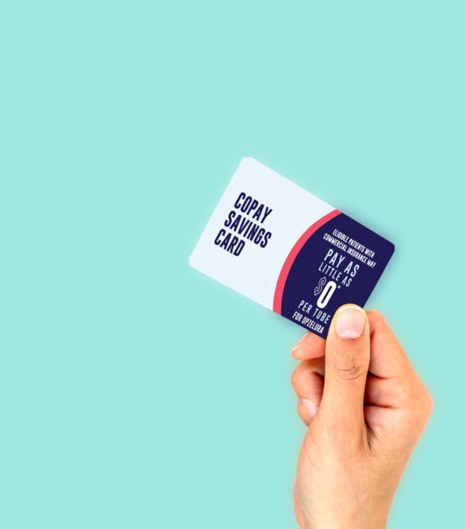 A hand holding a drug coupon savings card on a teal background, representing the drug coupons tool for reducing prescription costs