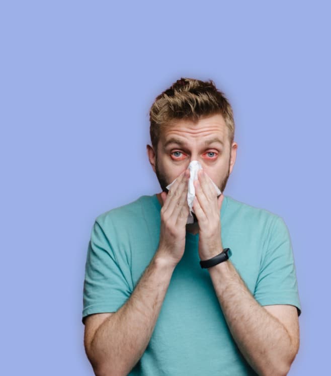 A man blowing his nose and showing signs of illness on a blue background, representing the AI-powered symptom assessment tool