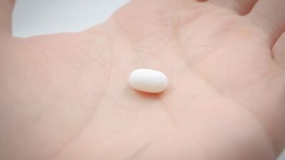 A single white Amycretin pill resting on the palm of a hand.